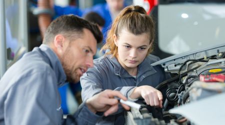 Young girl with male mentor fixing a car