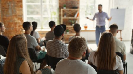 male teacher stood in front of a load of people