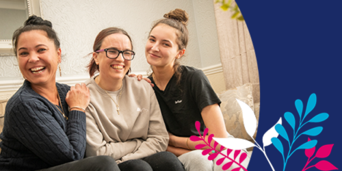 three women sat closely together smiling supportively