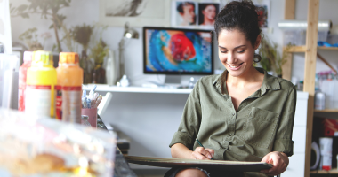 Woman smiling in a creative space sketching 