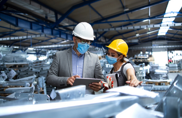 Production Manager Talking To Engineer wearing safety equipment 