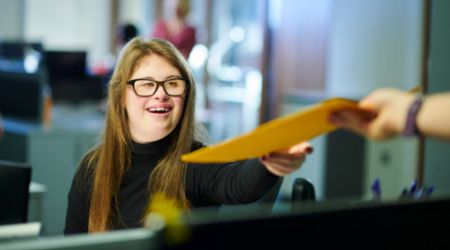 Lady being handed a yellow folder over a monitor