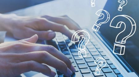 someone typing on a keyboard with doodled question marks over the top