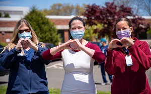 Care Workers Stood With Masks On Making Hearts Out Of Their Hands