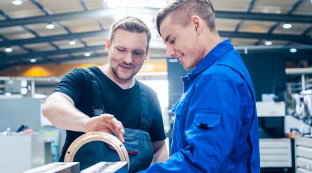 Man in manufacturing mentoring a young boy