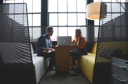 Two colleagues in a booth looking at laptop