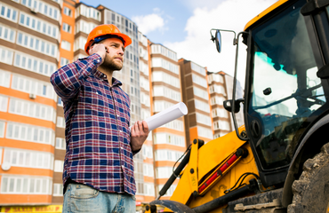 Site Worker Stood By Equipment On The Phone