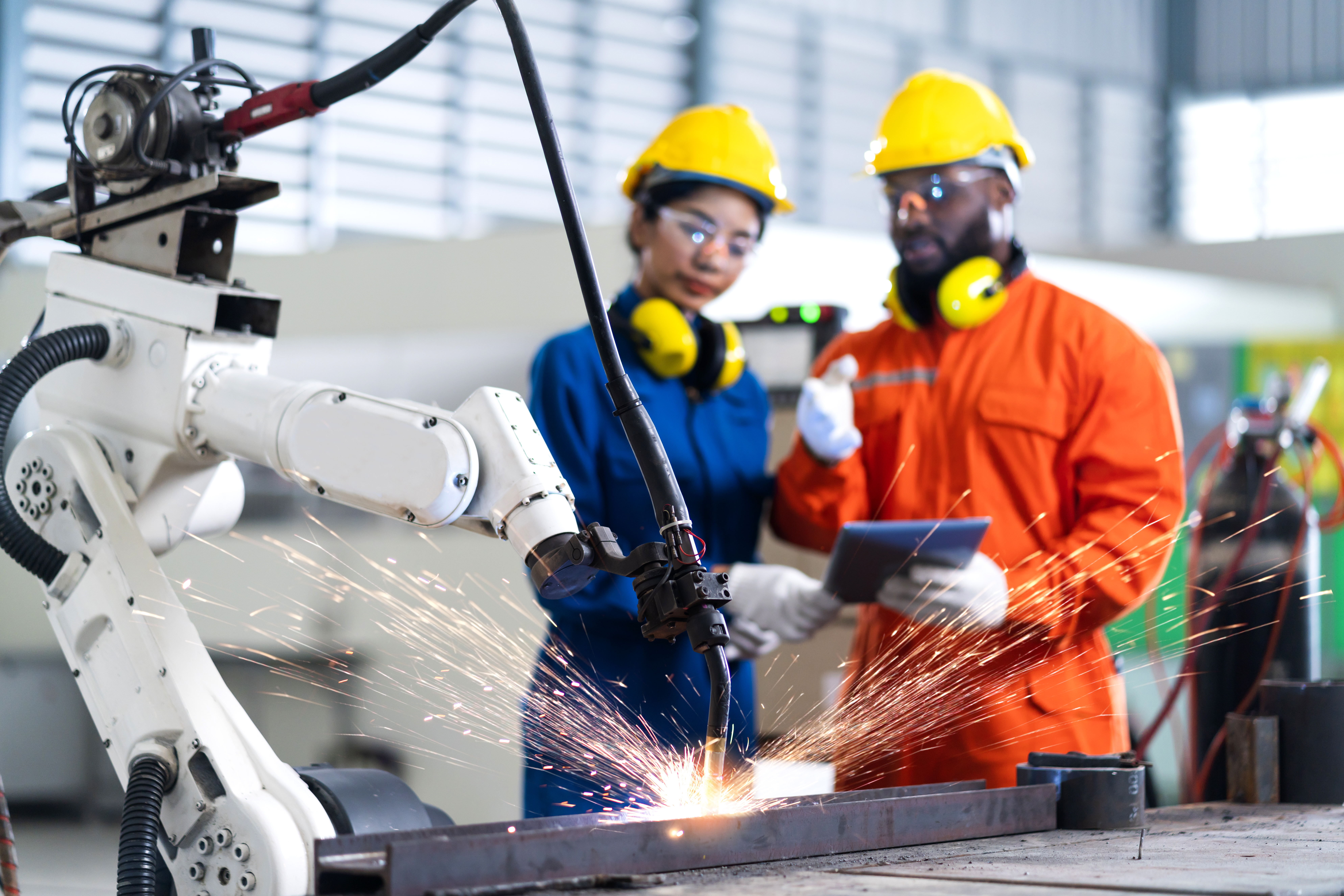 male and female engineering maintenance technicians supervising robot arm welding