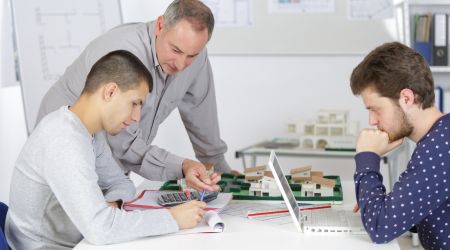 Three men around a table being mentored in architecture