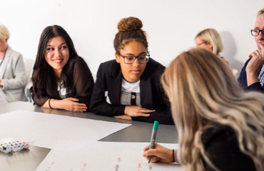 group of female office workers in a meeting writing on a large piece of paper 