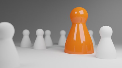 Orange chess piece amongst white pieces 