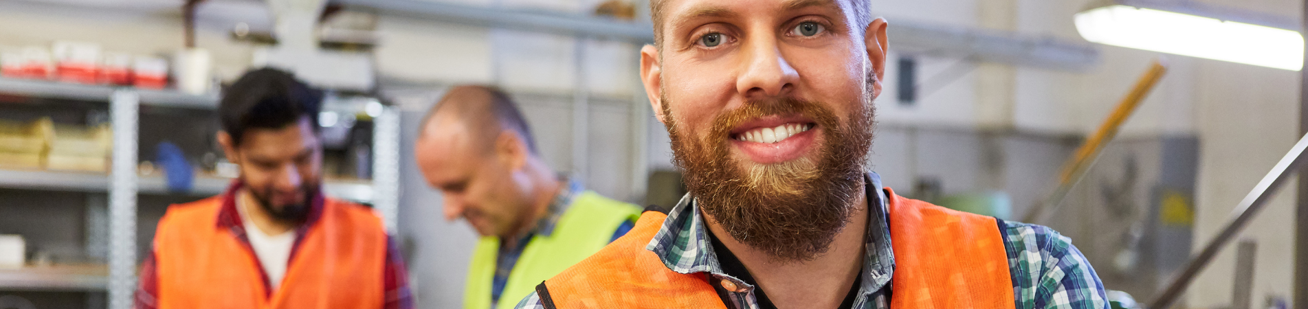 Man wearing high-vis smiling with two colleagues in background