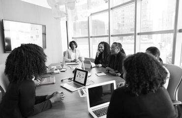 Group In A Meeting Room With Laptops Smiling And Talking