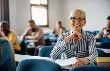 Over 50s woman wearing glasses smiling in a classroom 