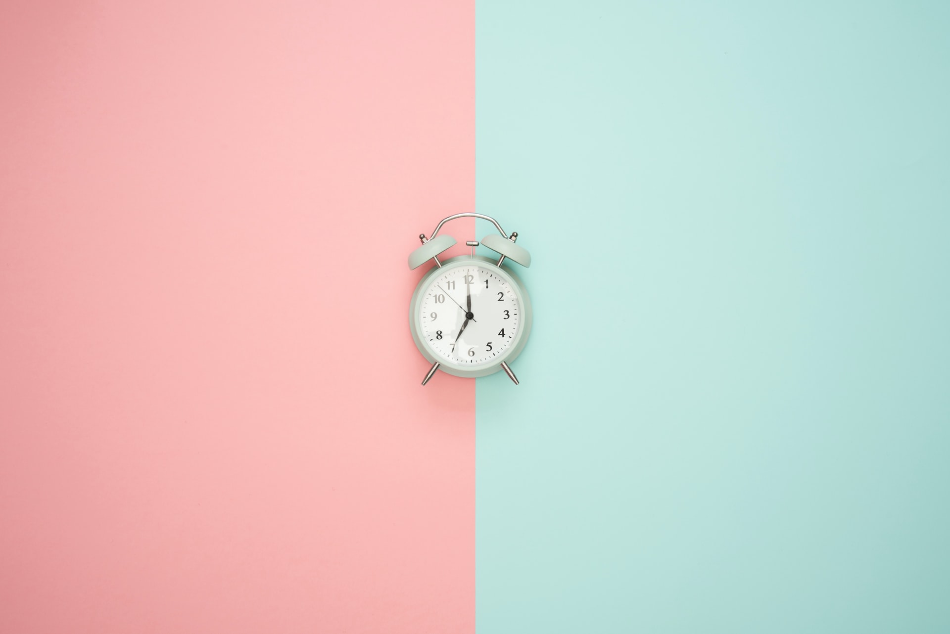 Light pink and blue background with alarm clock in centre
