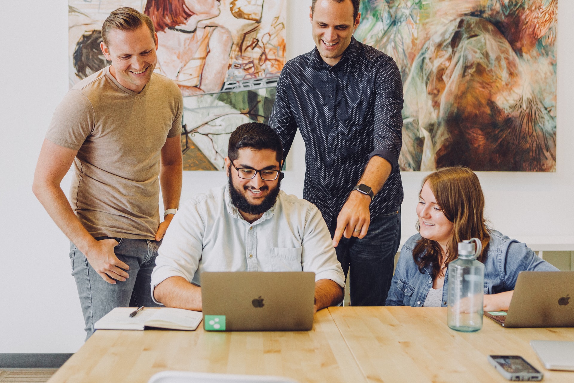 Group stood over desk looking at laptop