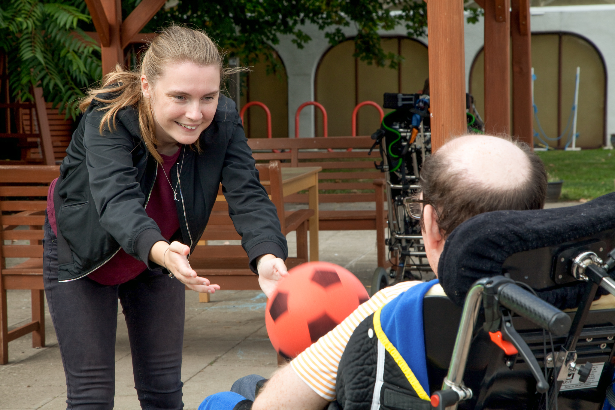 Carer Playing Ball Game With Man In Wheelchair